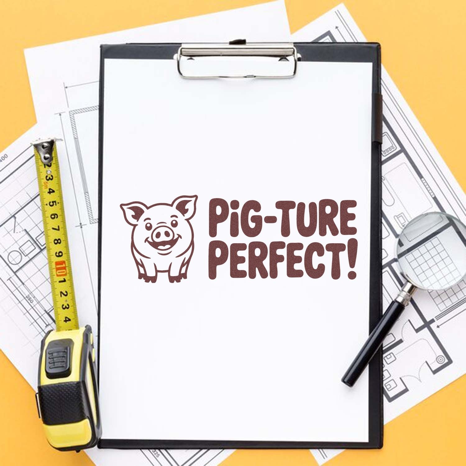 Pig-ture Perfect custom rubber stamp on clipboard with measuring tape and blueprints for construction projects.