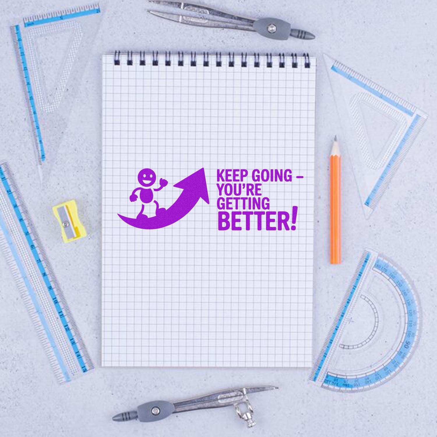 Motivational rubber stamp reading Keep Going - Youre Getting Better! on notebook, perfect for student encouragement.