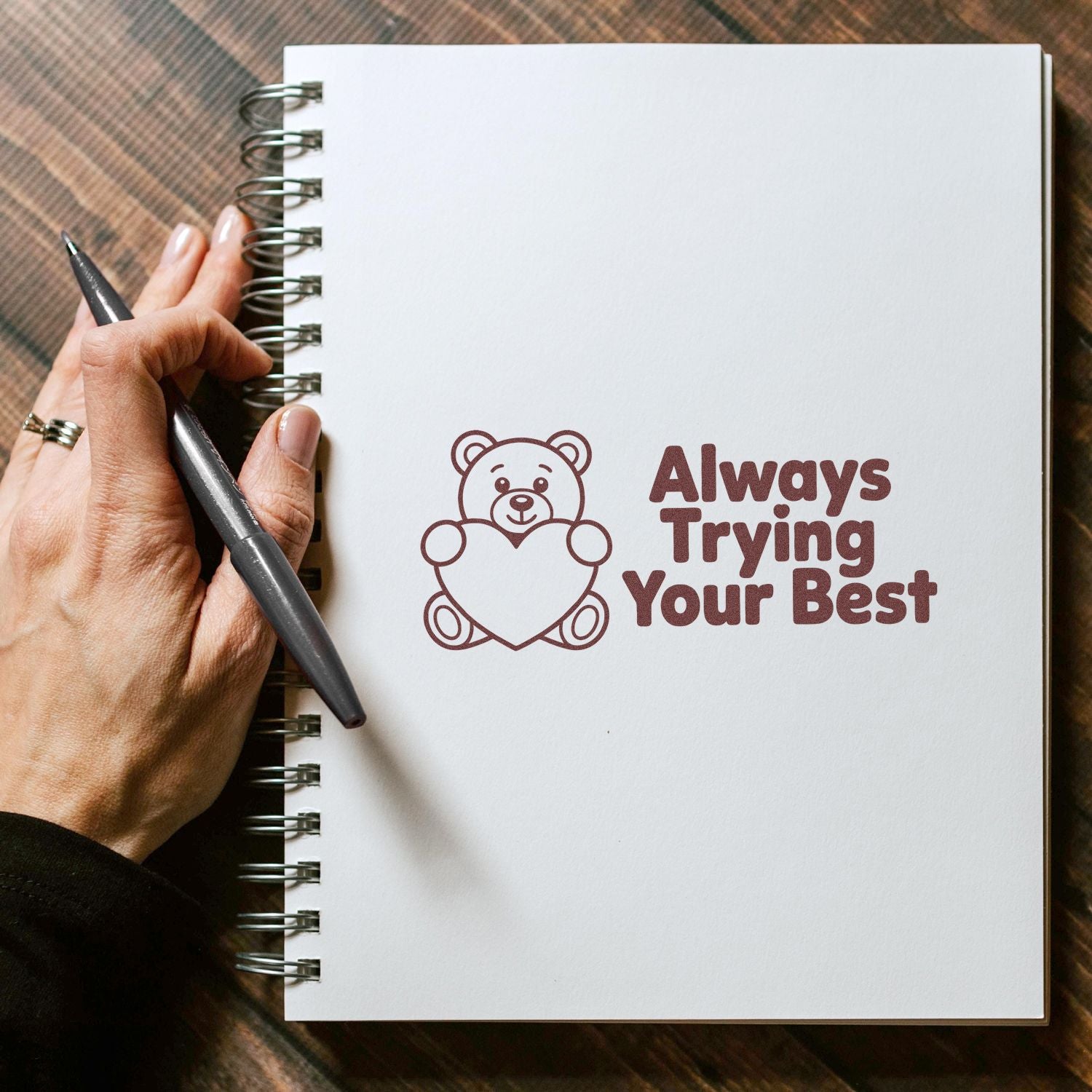 Inspirational bear holding heart rubber stamp with Always Trying Your Best on a spiral notebook.