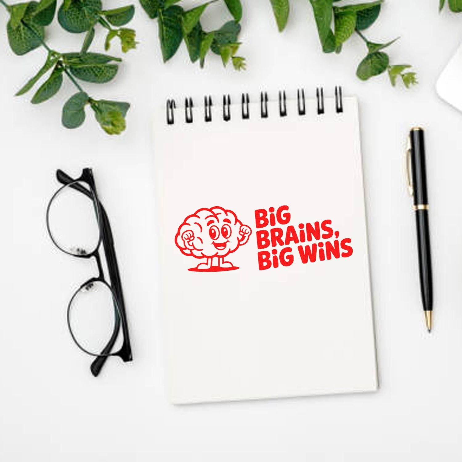 Big Brains, Big Wins rubber stamp design on notebook, a motivational office stamp with cartoon brain graphic.