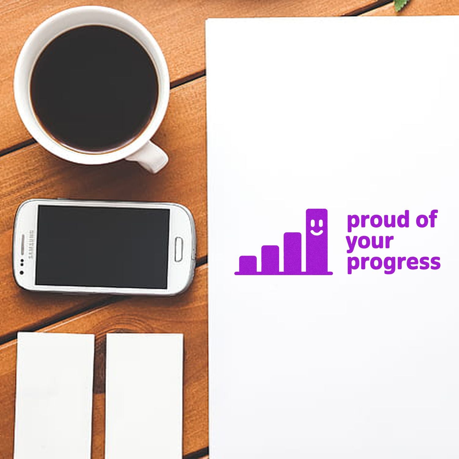 Rubber stamp design proof with Proud of Your Progress message, purple growth icon on paper beside coffee and smartphone.