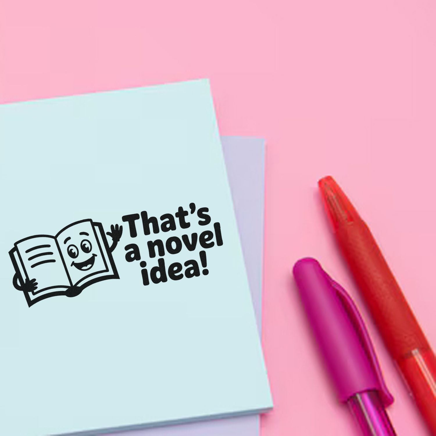 Custom rubber stamp with Thats a novel idea! and smiling book illustration on pastel stationery.
