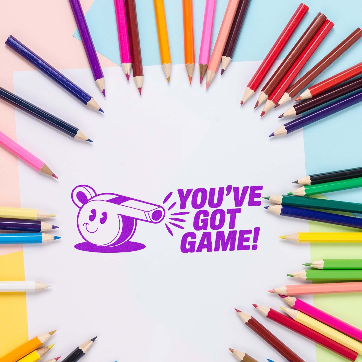 Custom rubber stamp design with Youve Got Game! text, framed by colorful pencils on white paper.