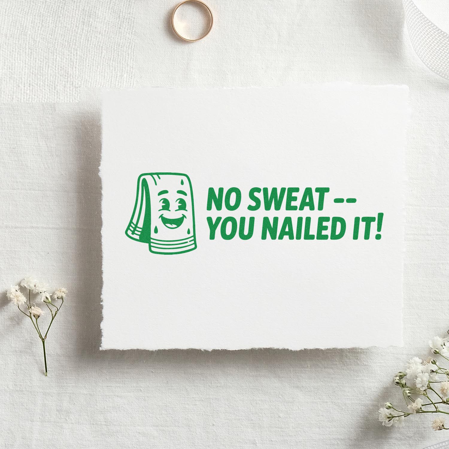 Green custom rubber stamp imprint with smiling towel and No Sweat -- You Nailed It! motivational message on white paper.