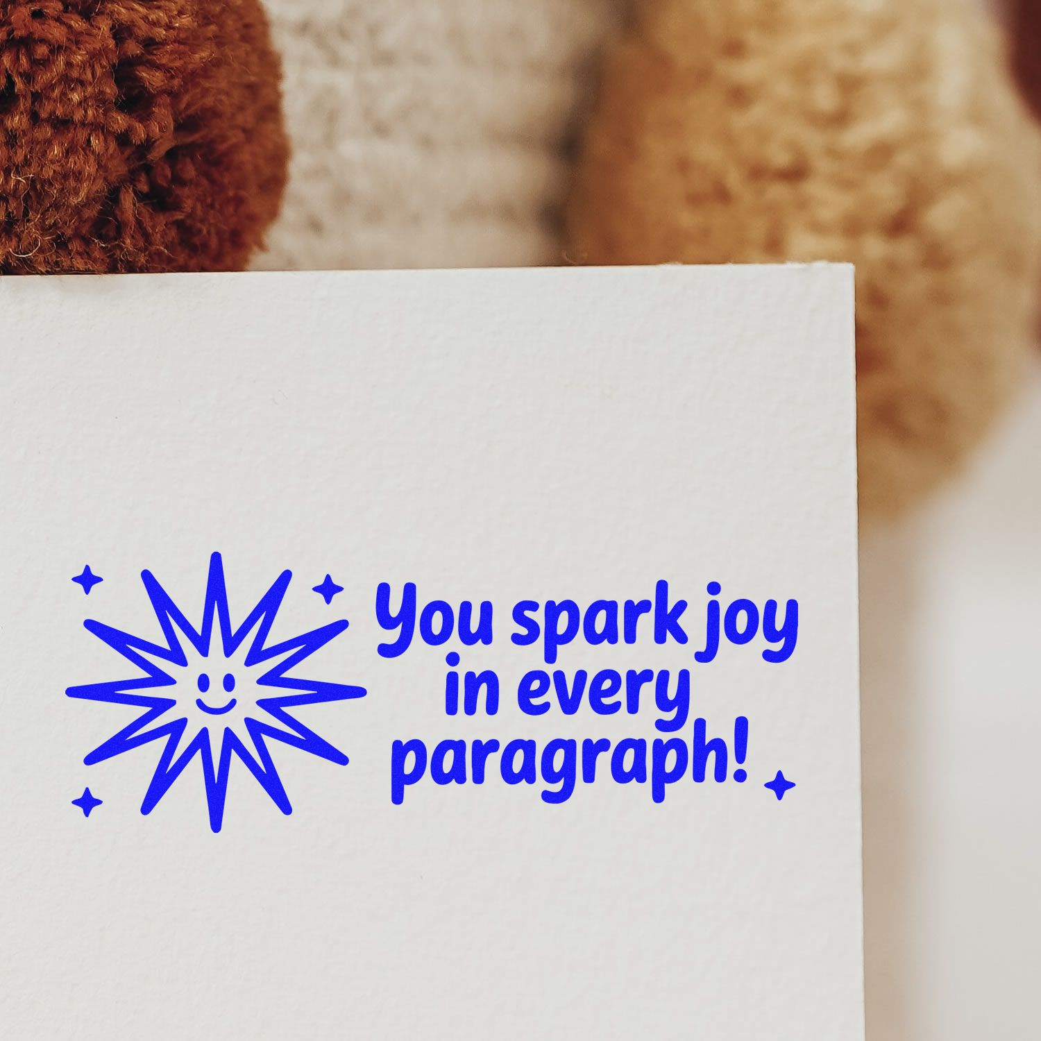 Custom rubber stamp reading You spark joy in every paragraph! with a smiling starburst design on white paper.