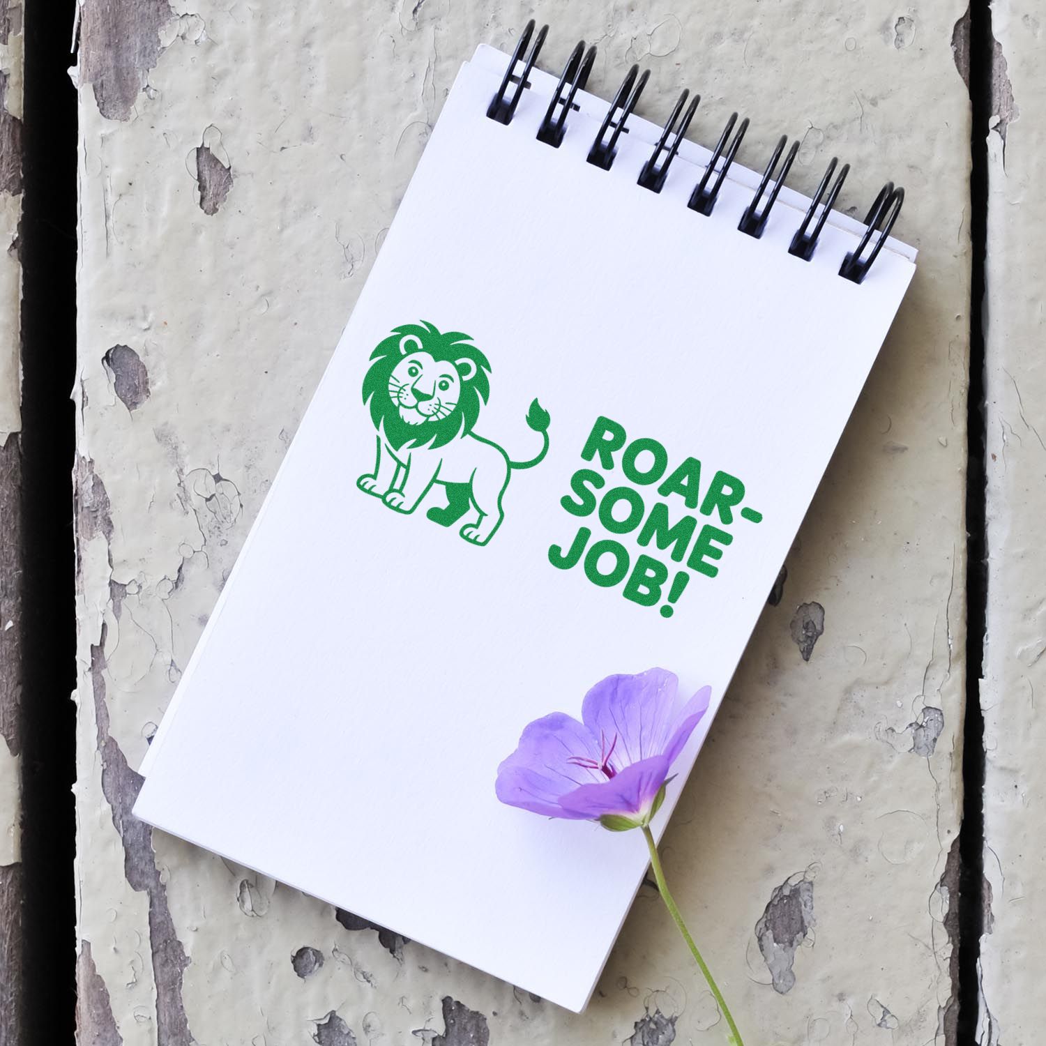 Custom lion rubber stamp mockup with Roar-some Job! on a spiral notebook for custom teacher stamps.