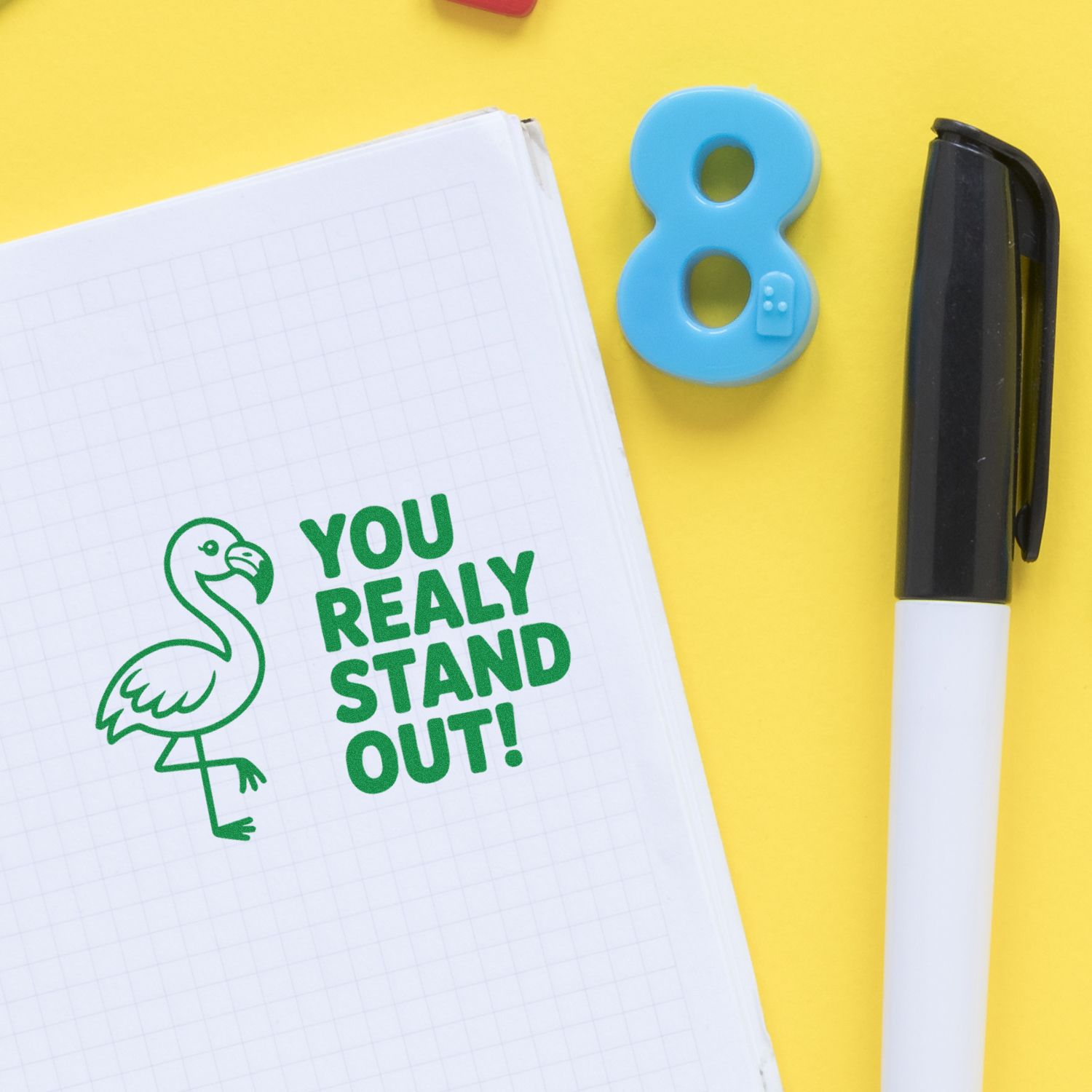 Flamingo rubber stamp imprint with You Really Stand Out! on notebook, showcasing a custom motivational stamp design.