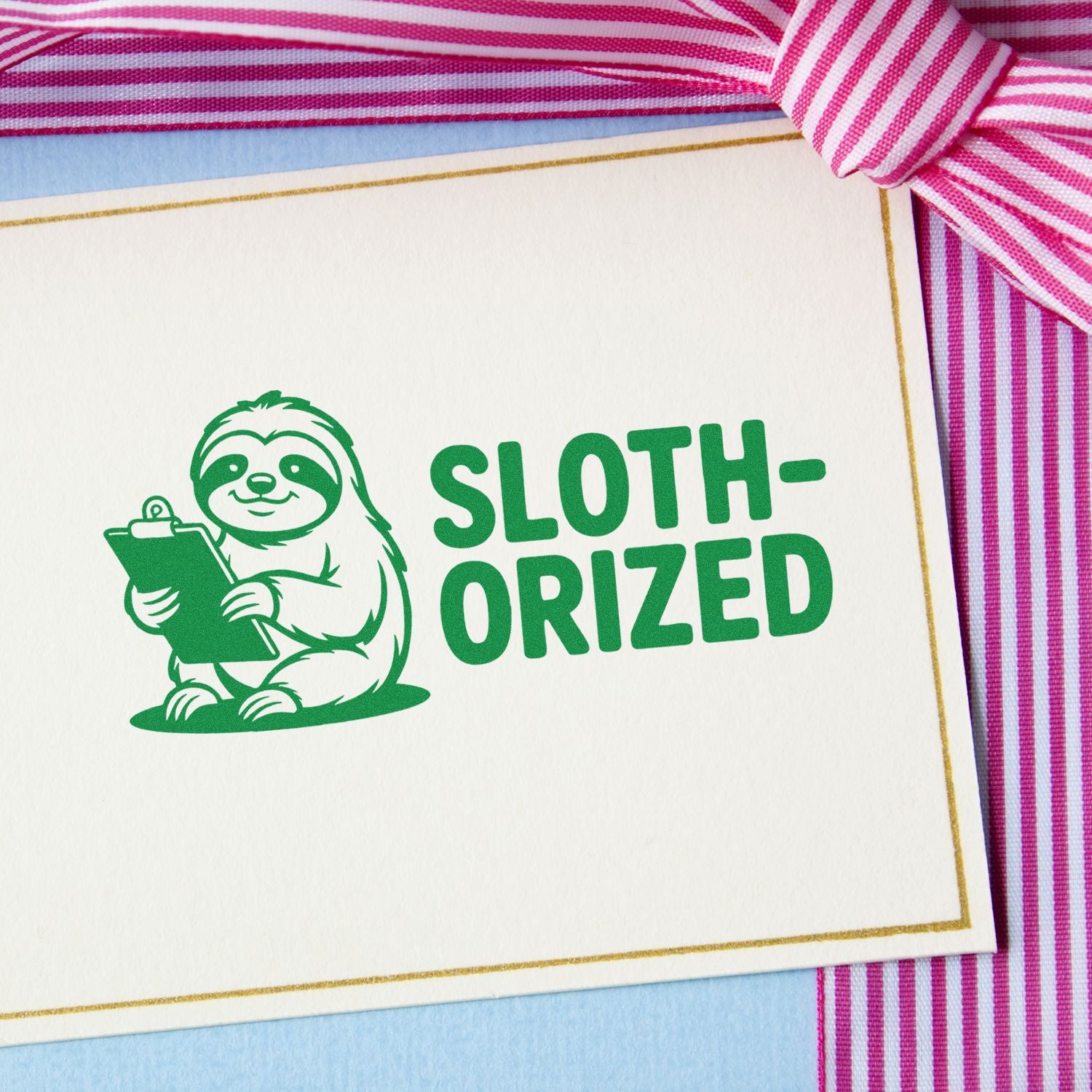 Green sloth-oriz??ed rubber stamp on a greeting card with pink ribbon, ideal for handmade stationery and craft projects.