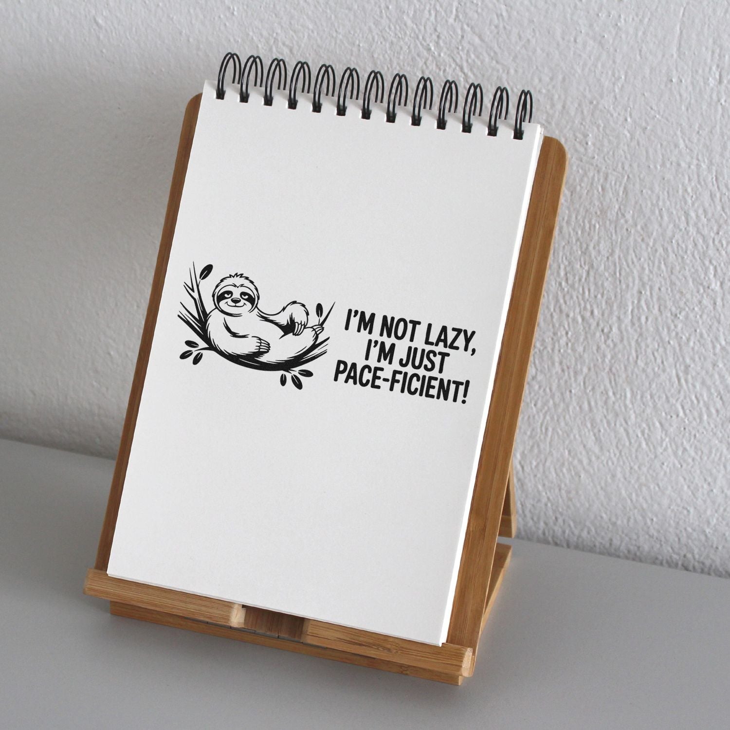 Sloth rubber stamp design reading Im not lazy, Im just pace-efficient! on a notebook display page.