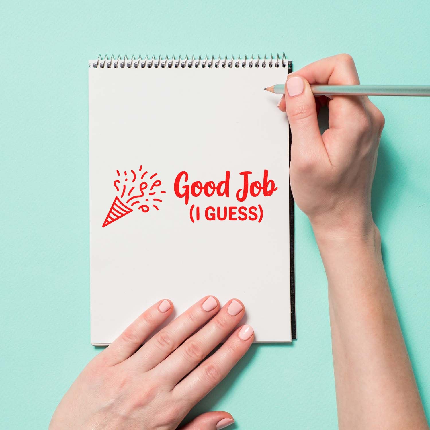 Custom rubber stamp reading Good Job (I Guess) stamped on a notebook page, with confetti icon and pencil in hand.