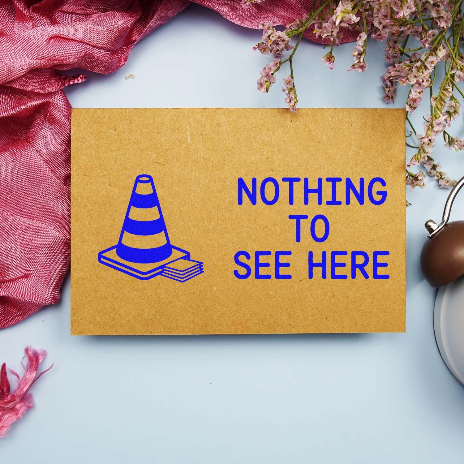 Custom rubber stamp design reading Nothing to See Here with cone icon on kraft paper for funny office or packaging use.