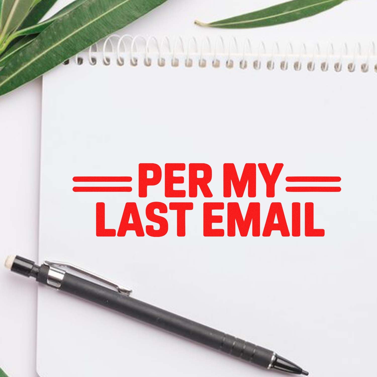 Rubber stamp with Per My Last Email text for office communication and email follow-up on a notebook with pen.