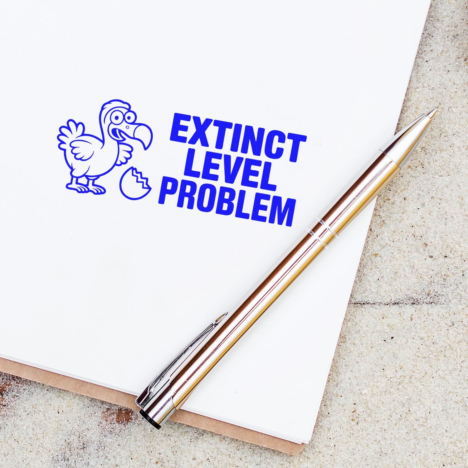 Funny dodo bird rubber stamp reading Extinct Level Problem on a notebook with pen, perfect for quirky custom stamp designs