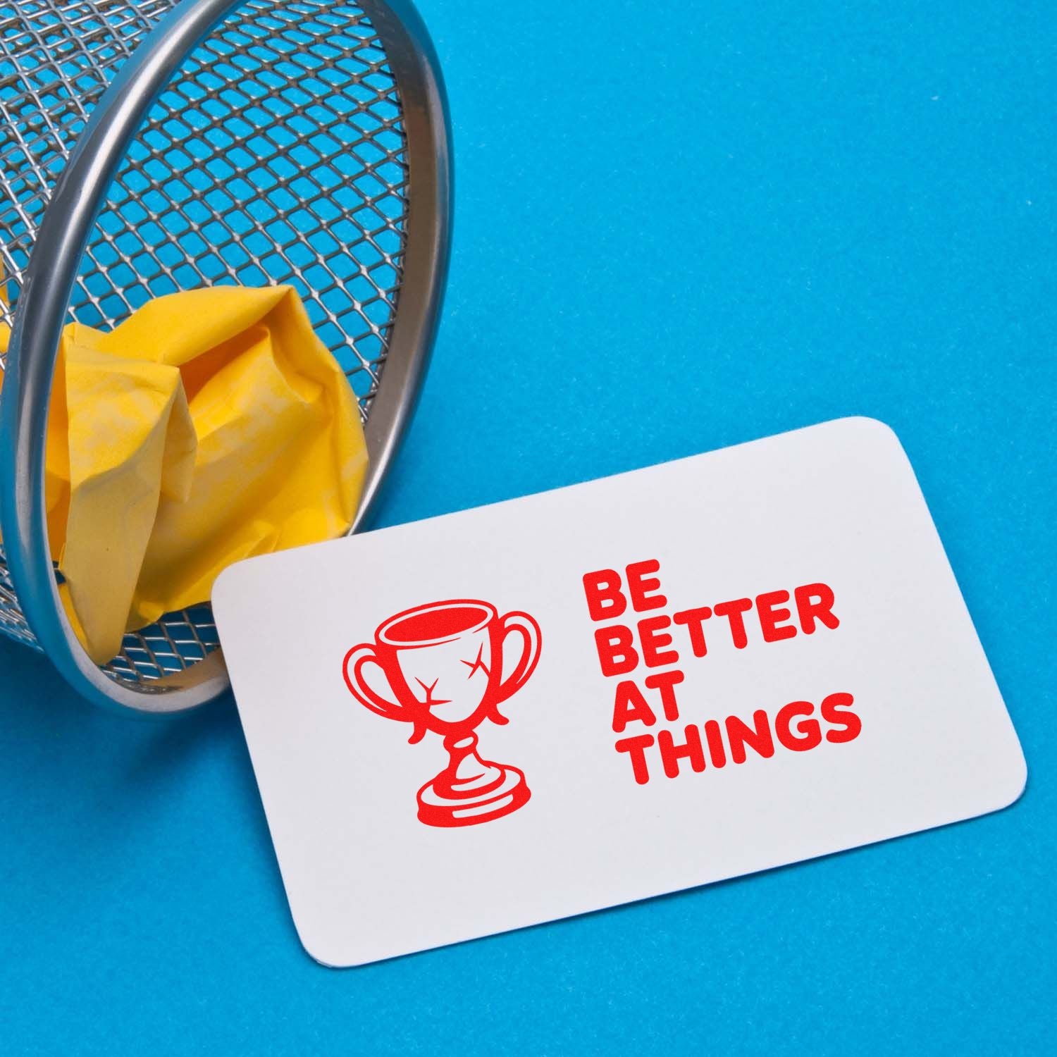 Motivational rubber stamp design with trophy icon and Be Better at Things slogan on a sample card.