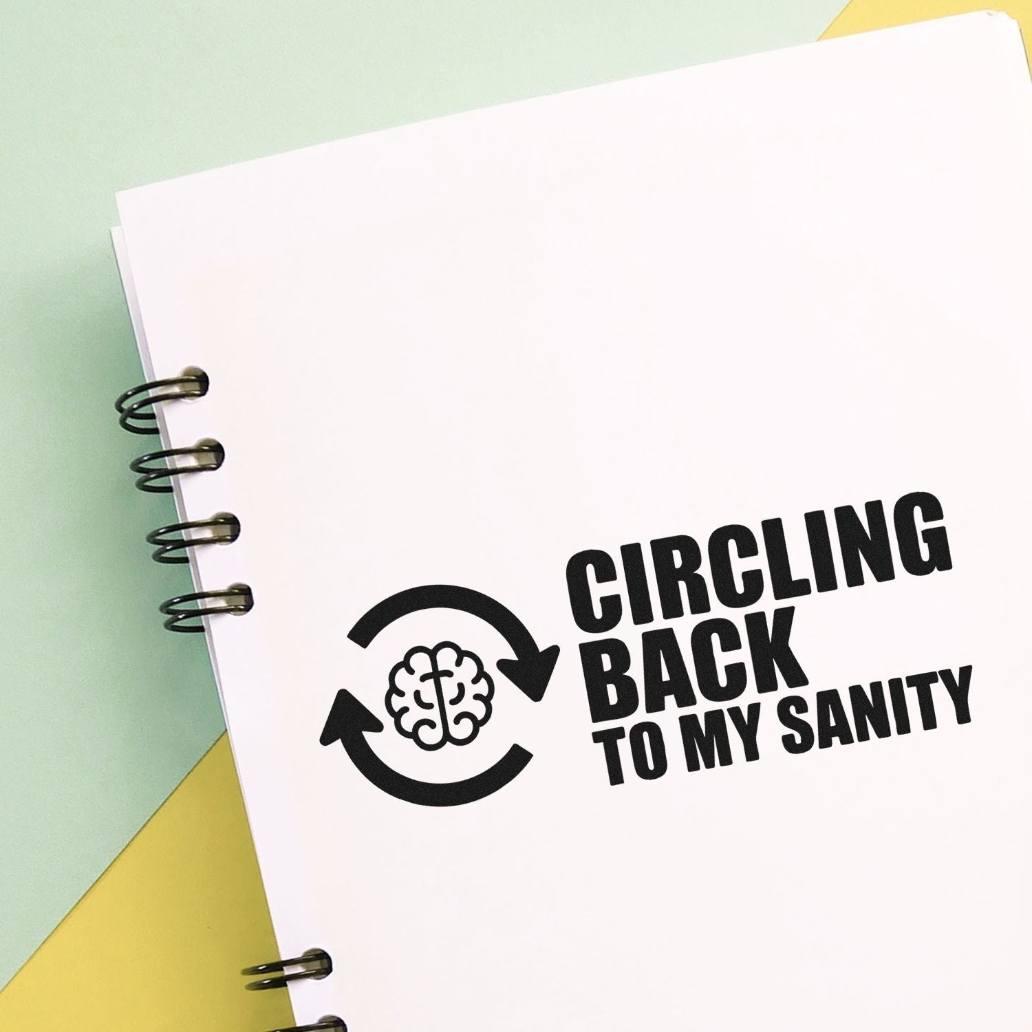 Humorous custom rubber stamp design reading Circling Back to My Sanity with brain and recycling arrows on a notebook page.