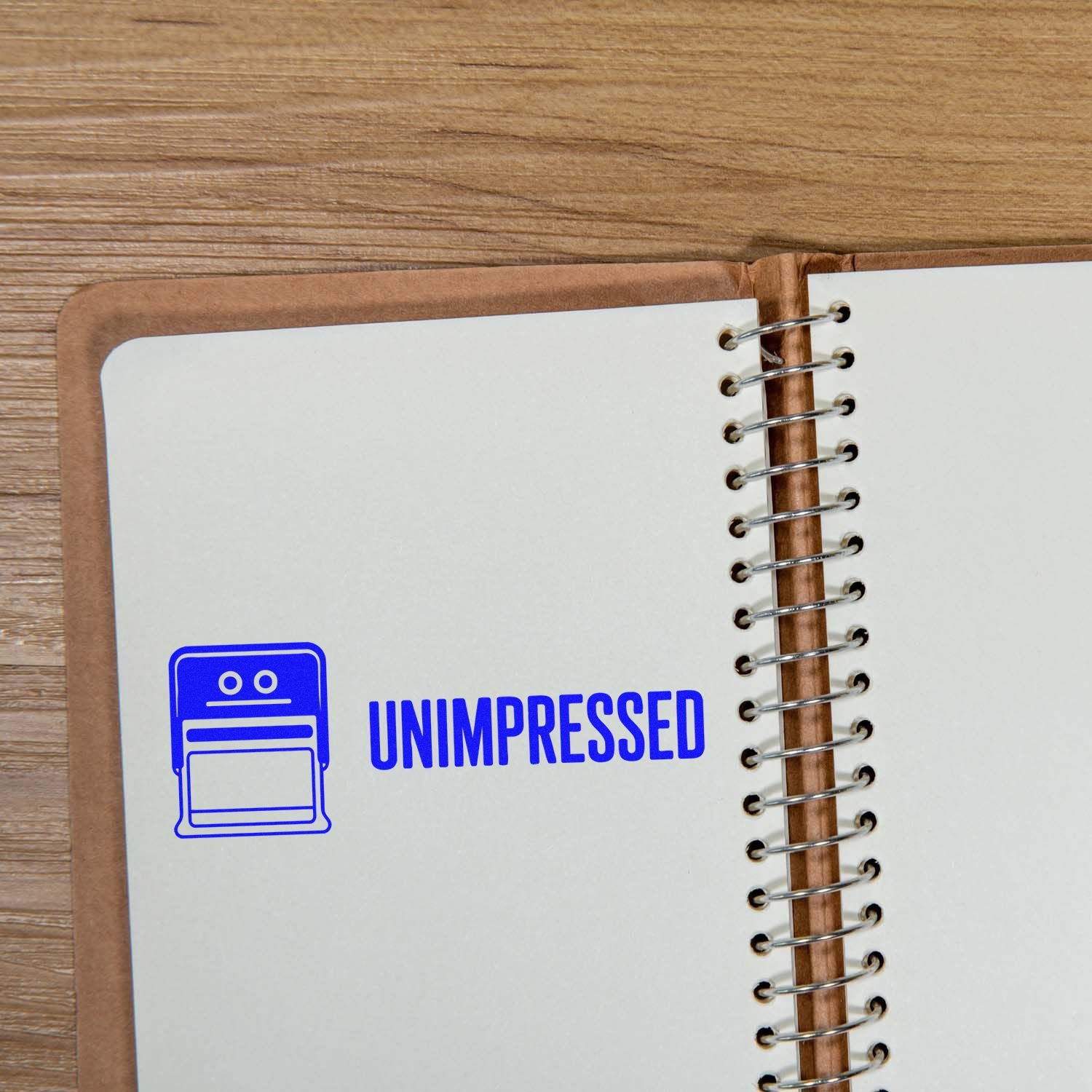 Blue Unimpressed rubber stamp on a spiral notebook page, ideal for custom office and stationery stamping.