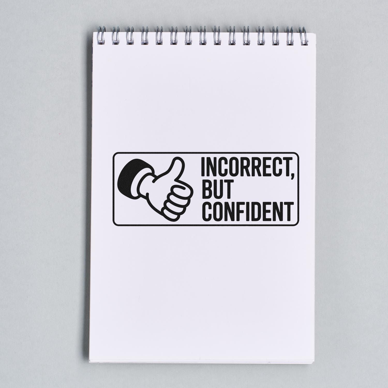 Humorous rubber stamp design on a notepad reading Incorrect, But Confident with thumbs-up icon for office use.