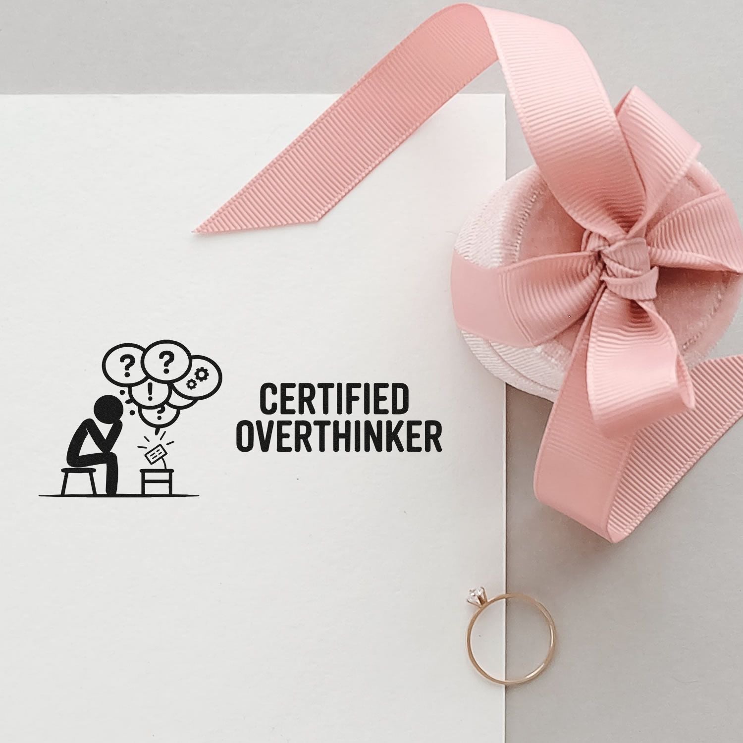 Custom rubber stamp with Certified Overthinker design on white stationery, styled with pink ribbon for personalized packaging.
