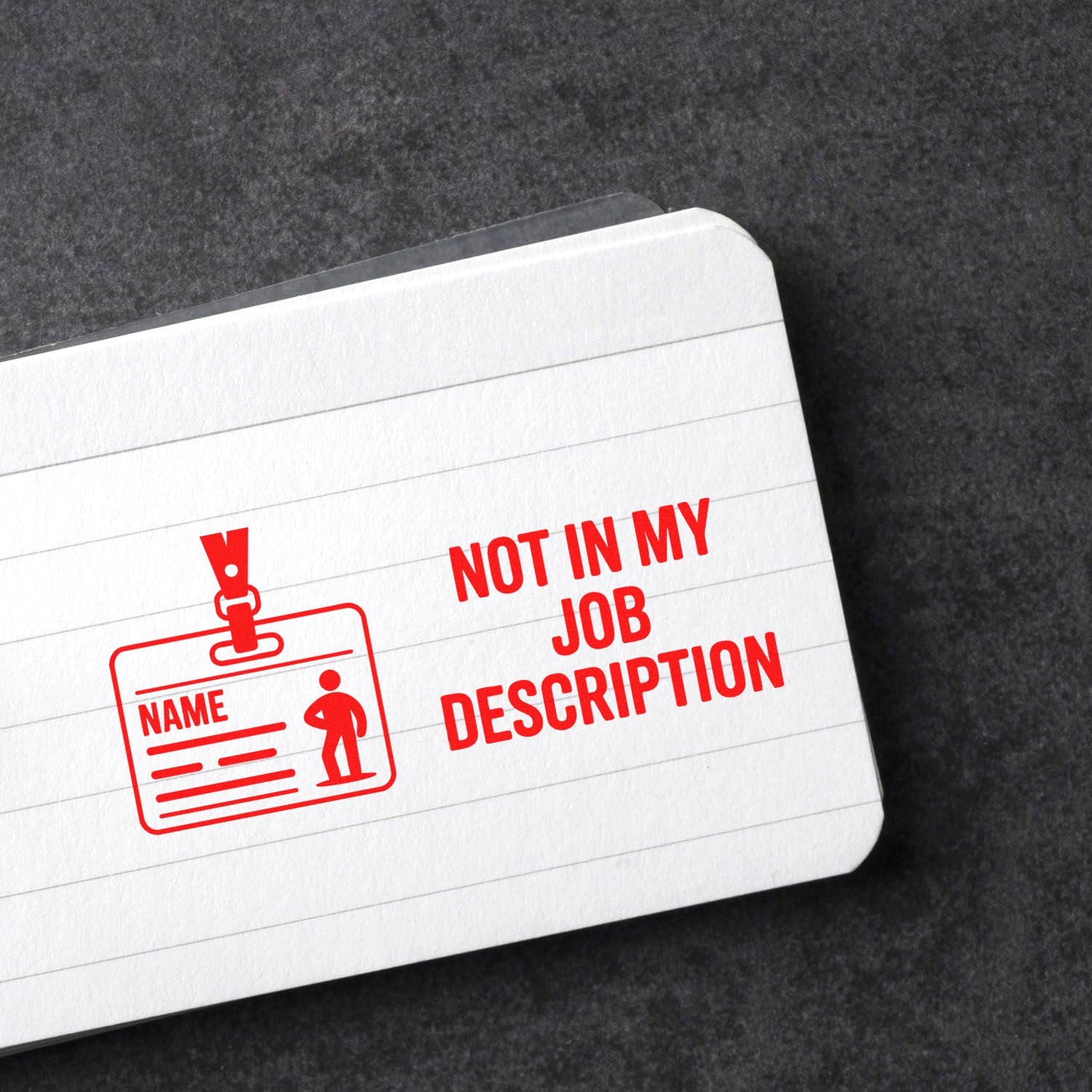 Custom rubber stamp design reading Not in My Job Description on a lined notebook page with employee badge icon.