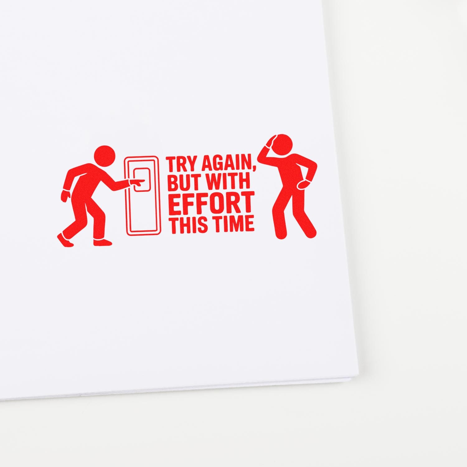 Red motivational rubber stamp reading "Try Again, But With Effort This Time" on white paper.