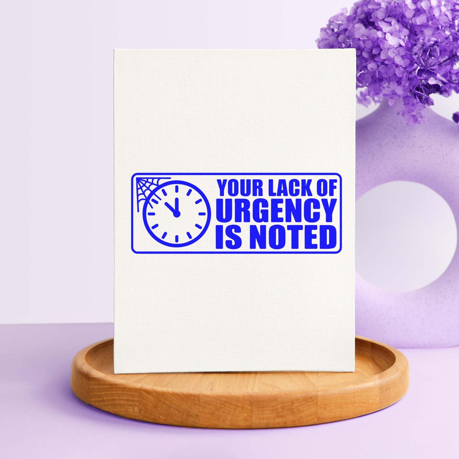Humorous rubber stamp with clock icon and bold text, Your Lack of Urgency Is Noted, for office and mail use.
