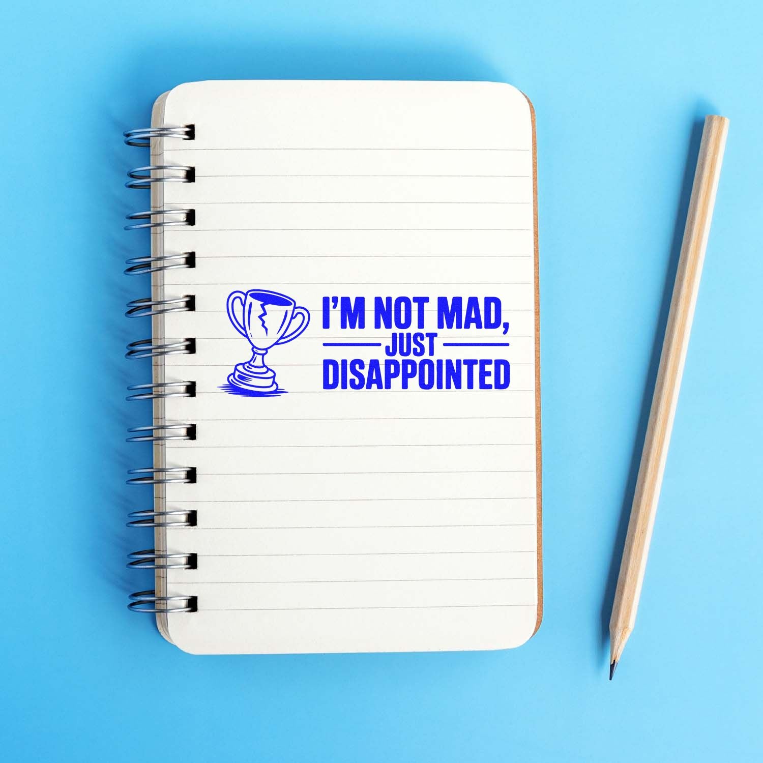 Rubber stamp design with trophy icon and Im not mad, just disappointed text on a notebook page.
