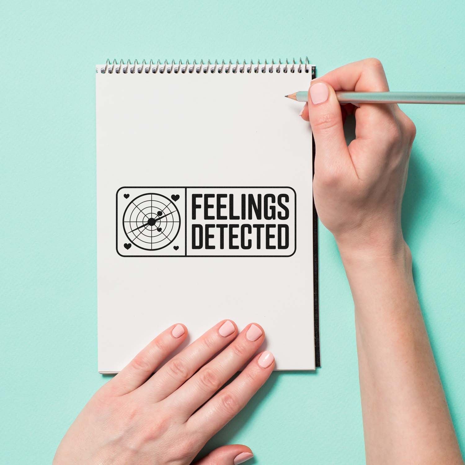 Funny rubber stamp design reading Feelings Detected on notebook mockup, ideal for journaling, planners, and crafts.