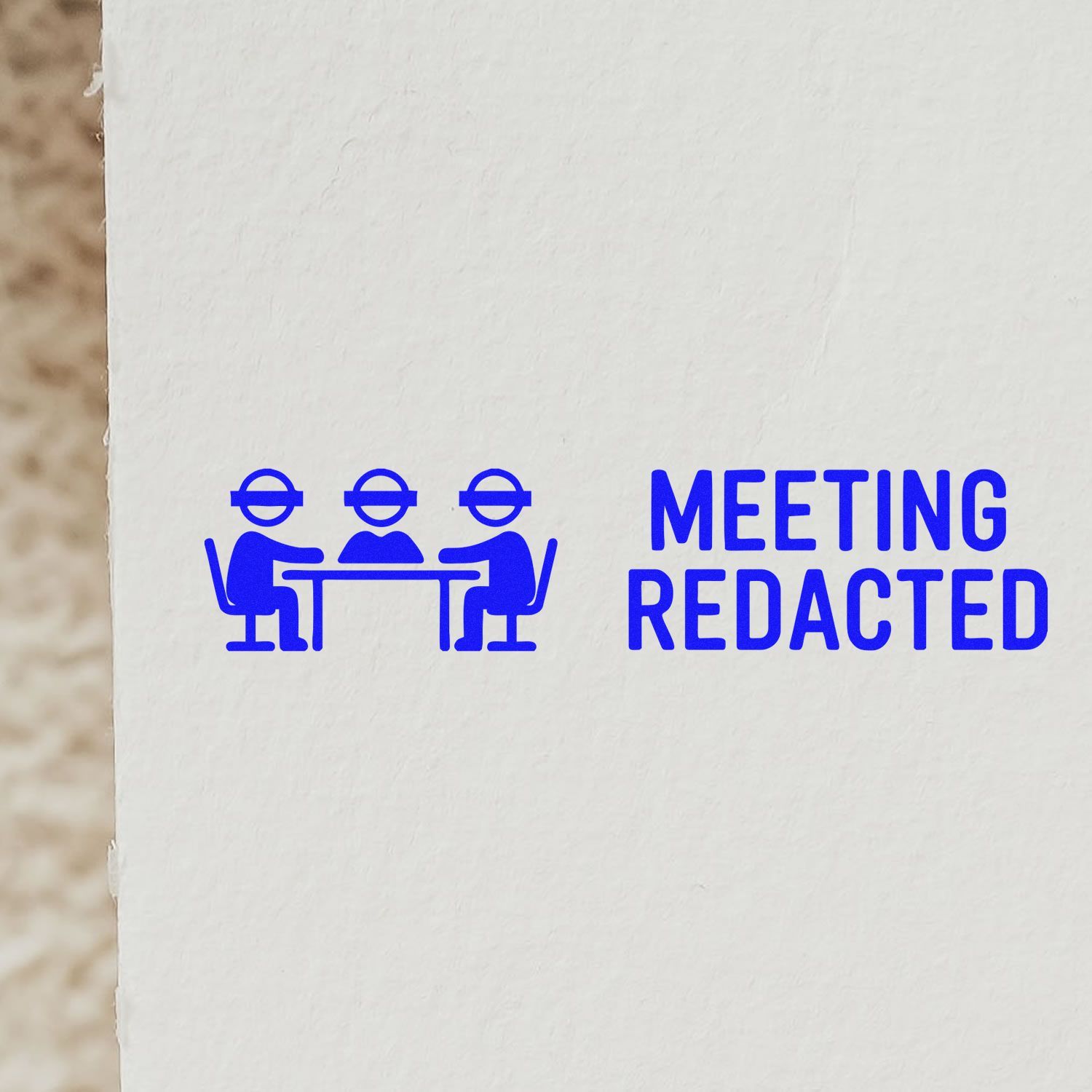 Blue custom rubber stamp impression reading Meeting Redacted with conference icon on paper.