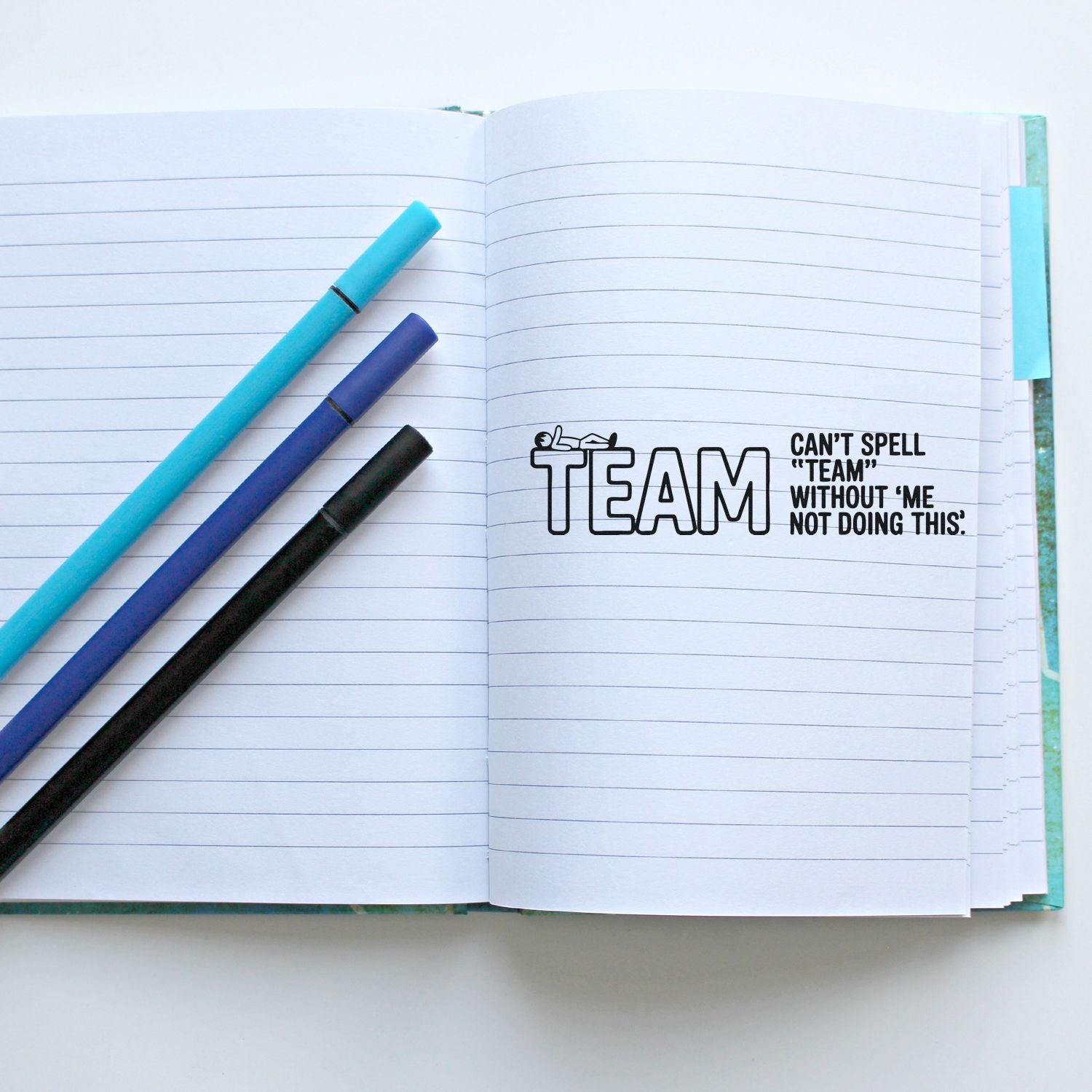 Funny team rubber stamp in a lined notebook, with pens, reading Cant spell team without me not doing this for office use.