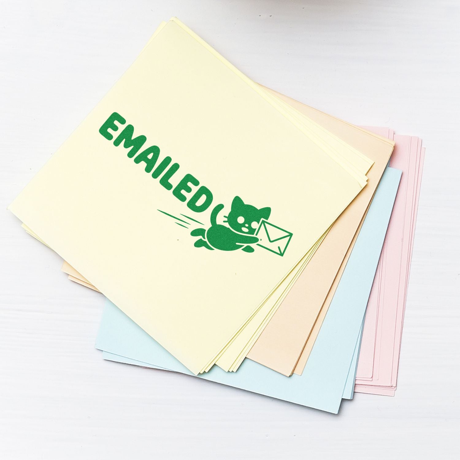 Green EMAILED rubber stamp on pastel office paper for mailroom document processing.