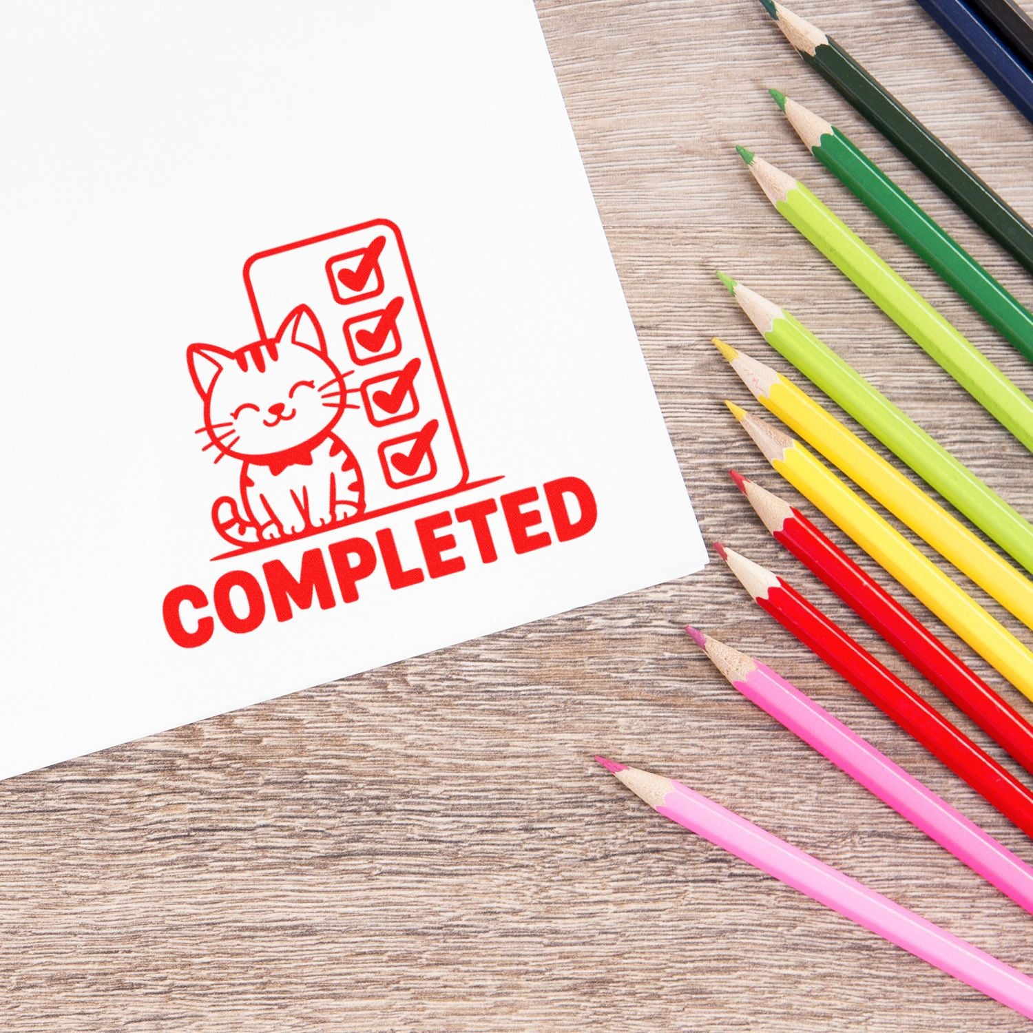 Custom rubber stamp with cat checklist and COMPLETED mark beside colored pencils on desk.