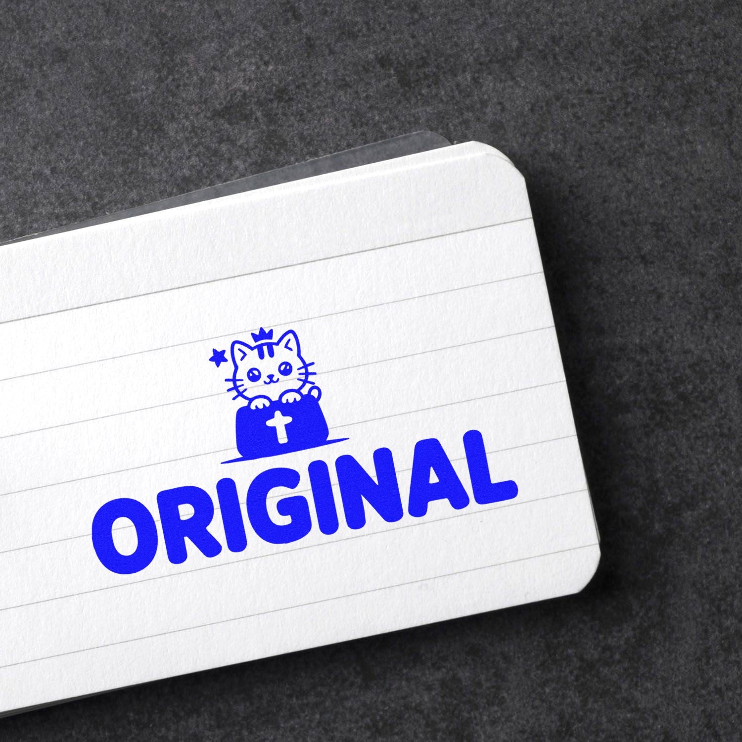 Blue Original rubber stamp with cat icon on lined notebook paper, marking handmade or unique designs.