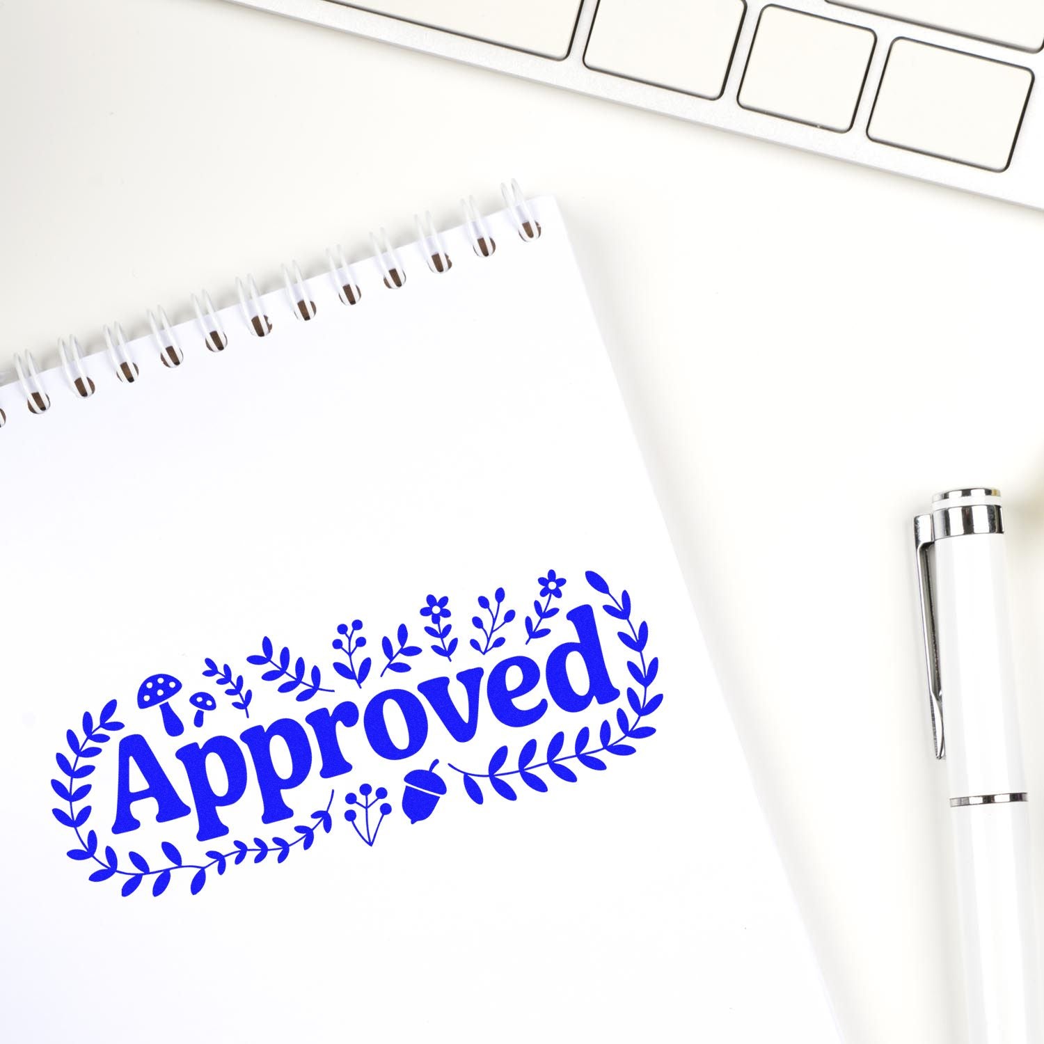 Blue Approved rubber stamp on a notebook beside a pen and laptop, ideal for office document approval and custom stamps.