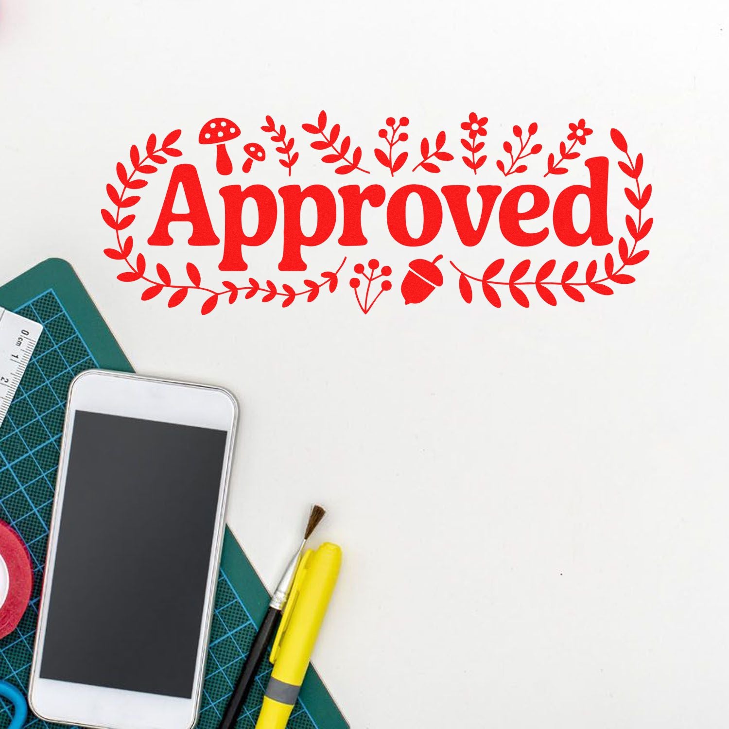 Red Approved rubber stamp with floral wreath on craft desk, ideal for handmade business, office, and scrapbooking.