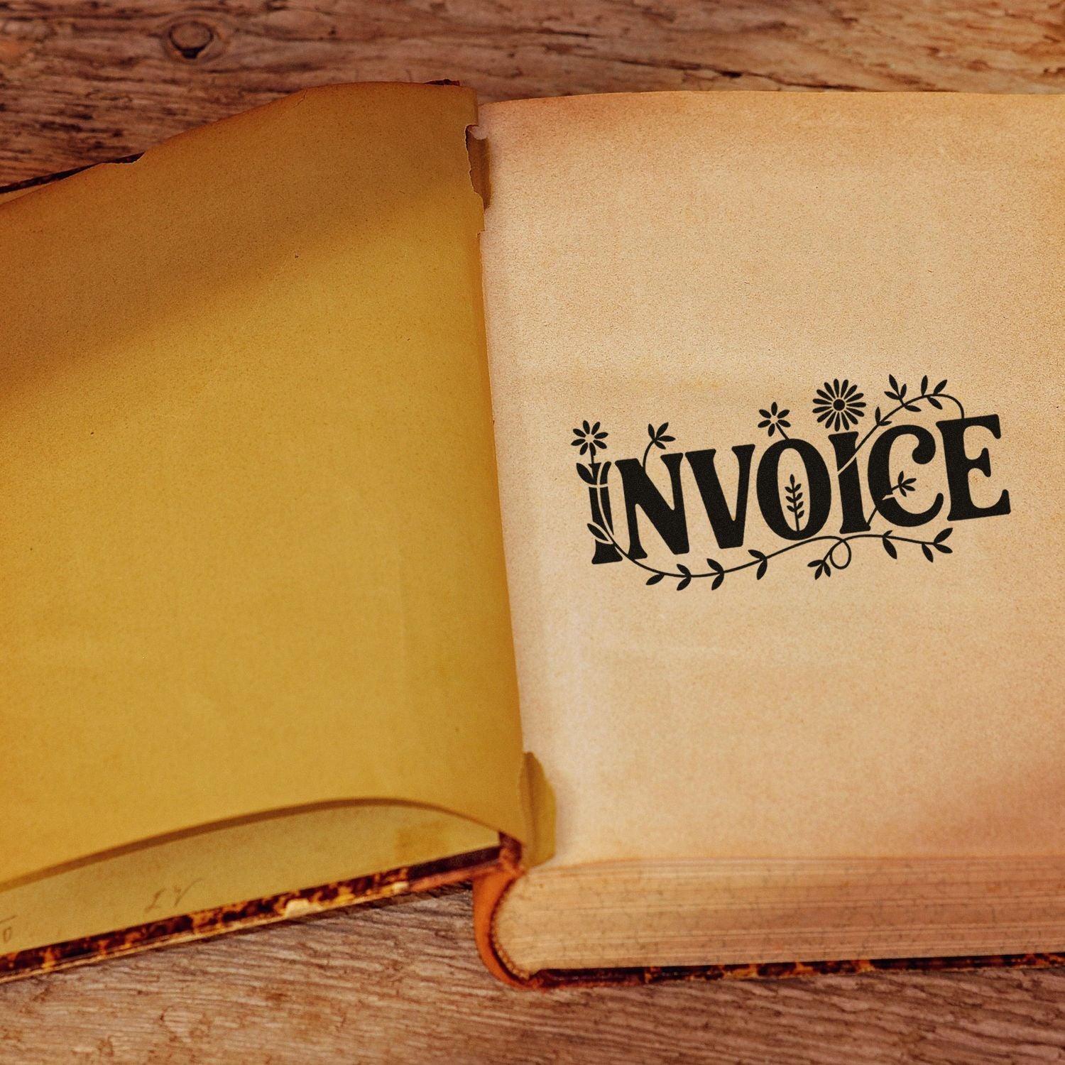 Decorative invoice rubber stamp on open ledger book page for business accounting and record keeping.