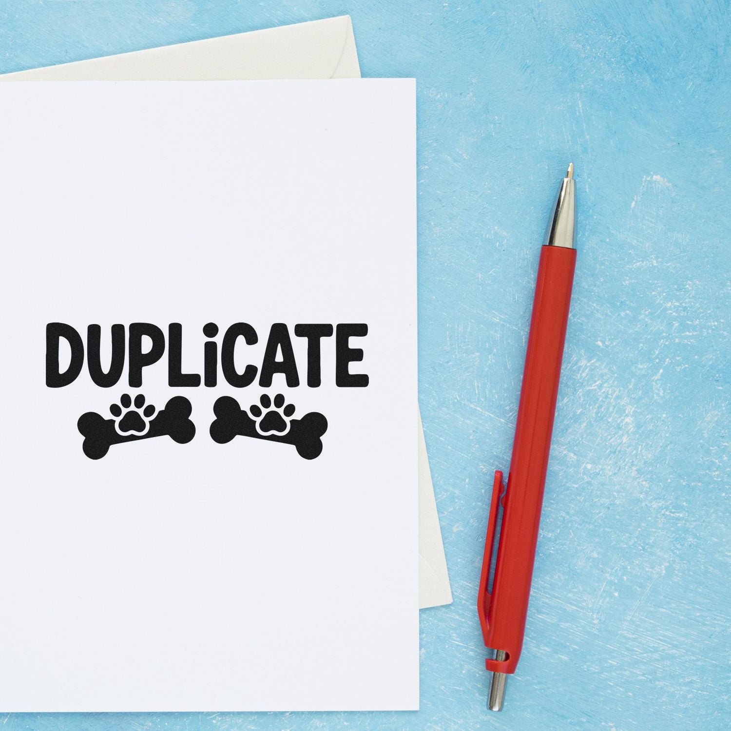 Duplicate rubber stamp with paw print icon, shown on paper beside a red penideal for office, filing, and pet records.