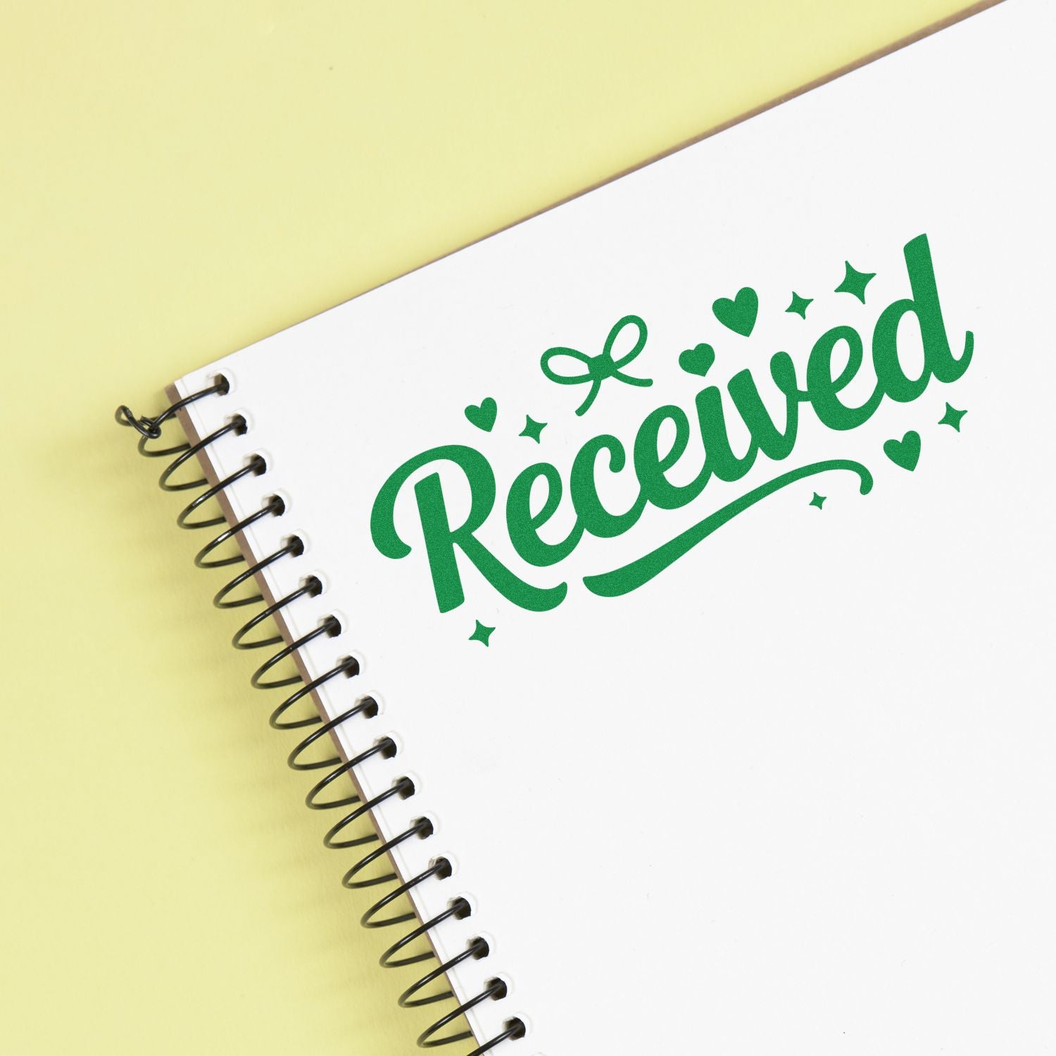 Green Received rubber stamp on spiral notebook, ideal for office document processing and approval tracking.