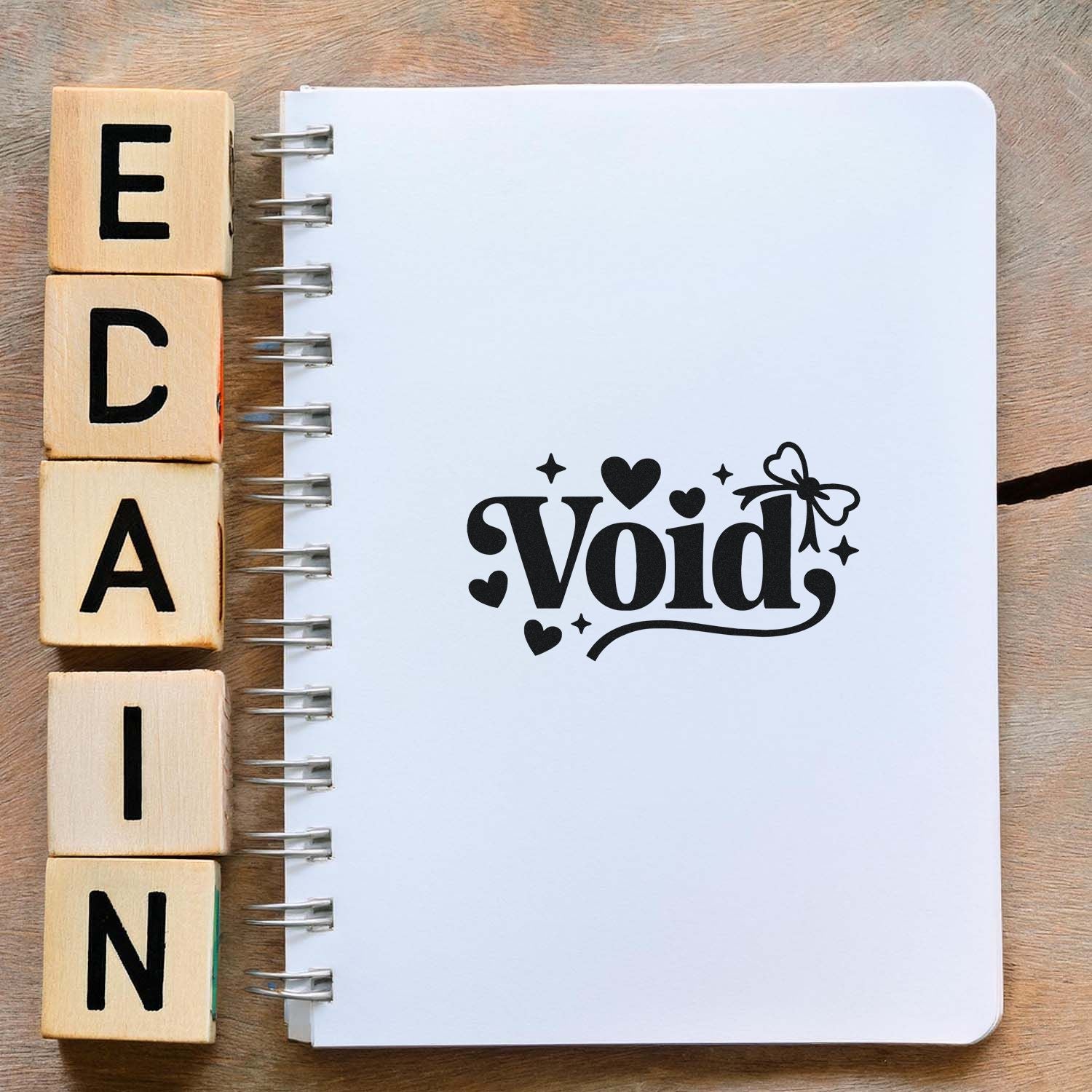 Decorative Void rubber stamp design in a notebook, shown beside wooden alphabet blocks for crafting and journaling.