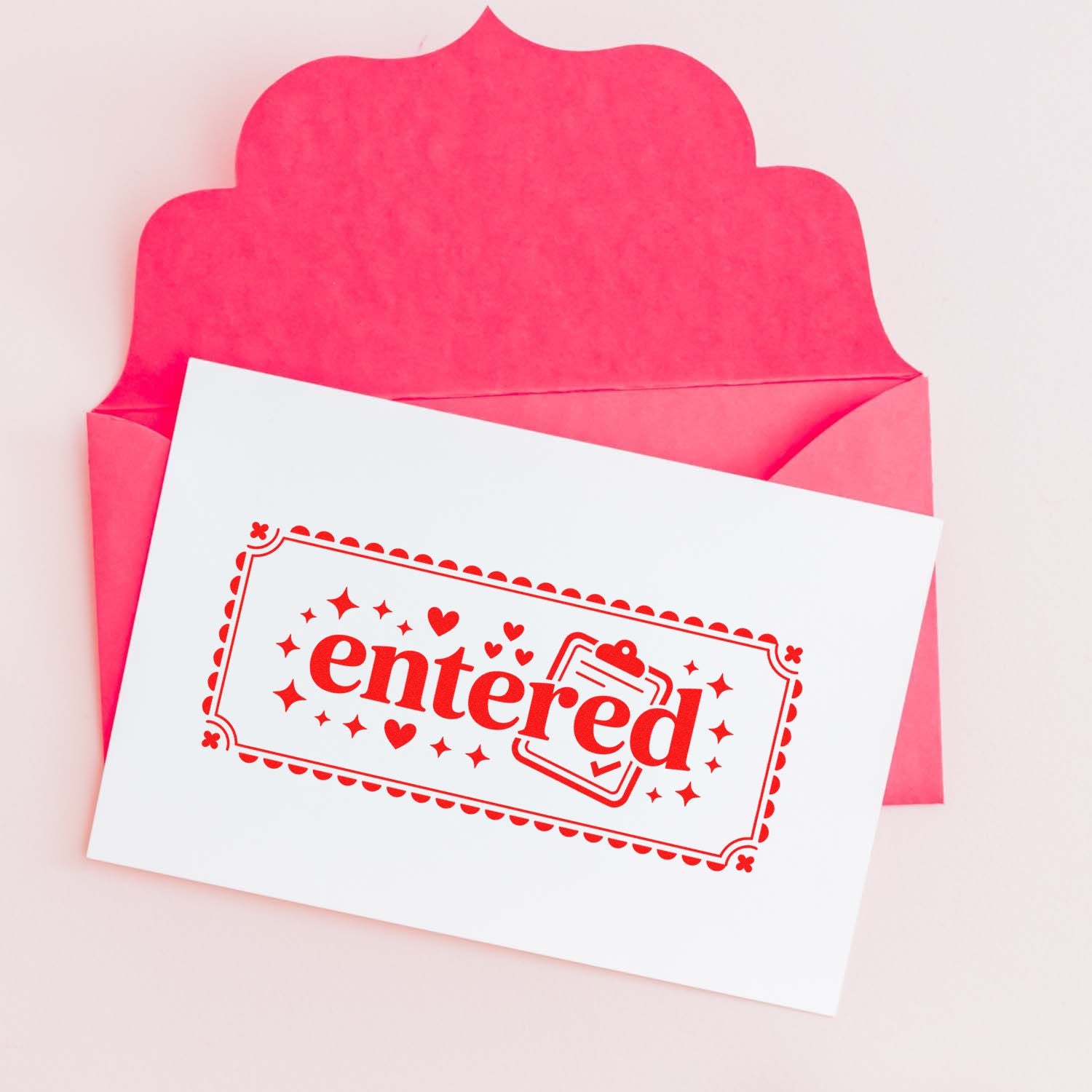 Custom entered rubber stamp design on a white card with pink envelope background.