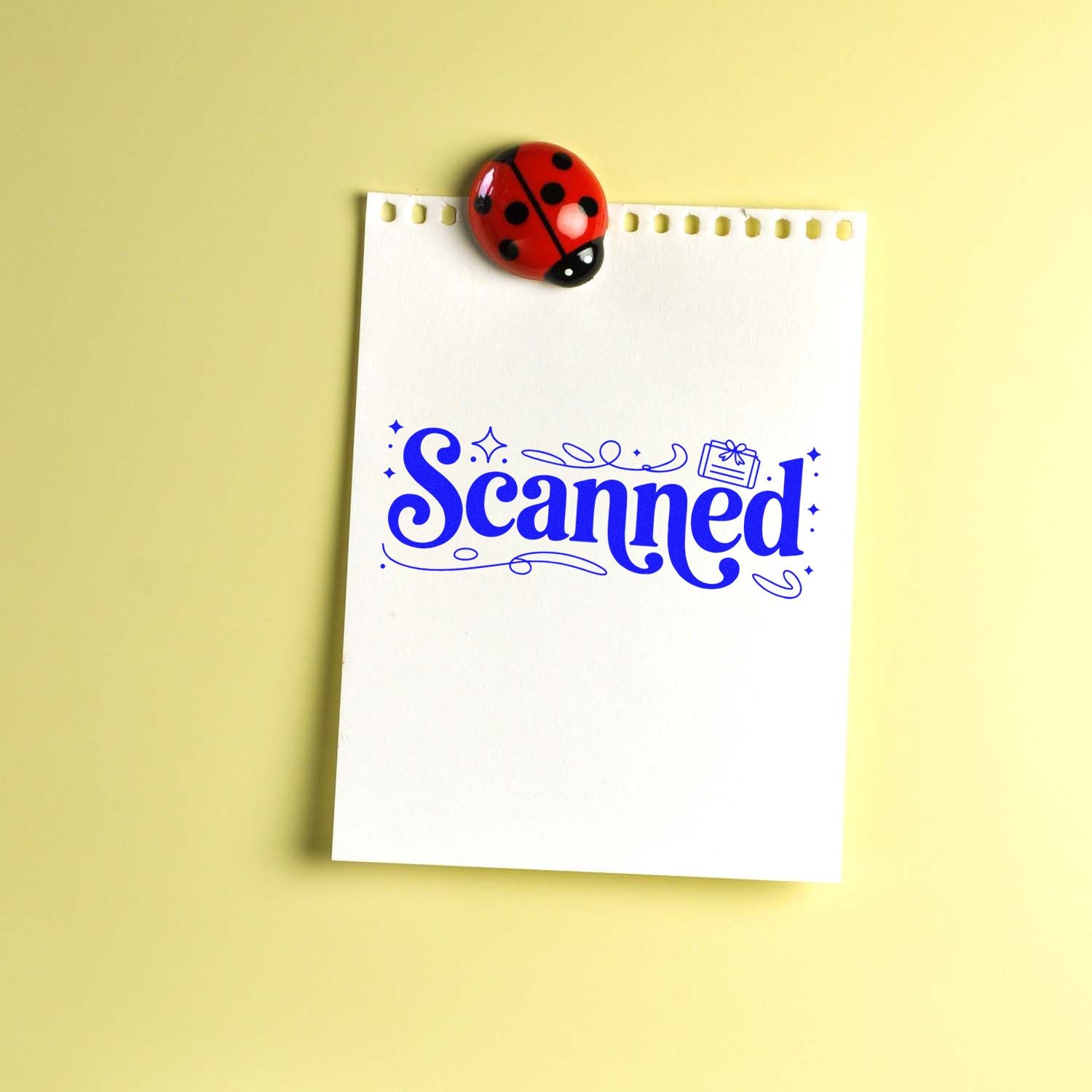 Blue Scanned rubber stamp design on notepad with ladybug clip, ideal for office document processing and organization.
