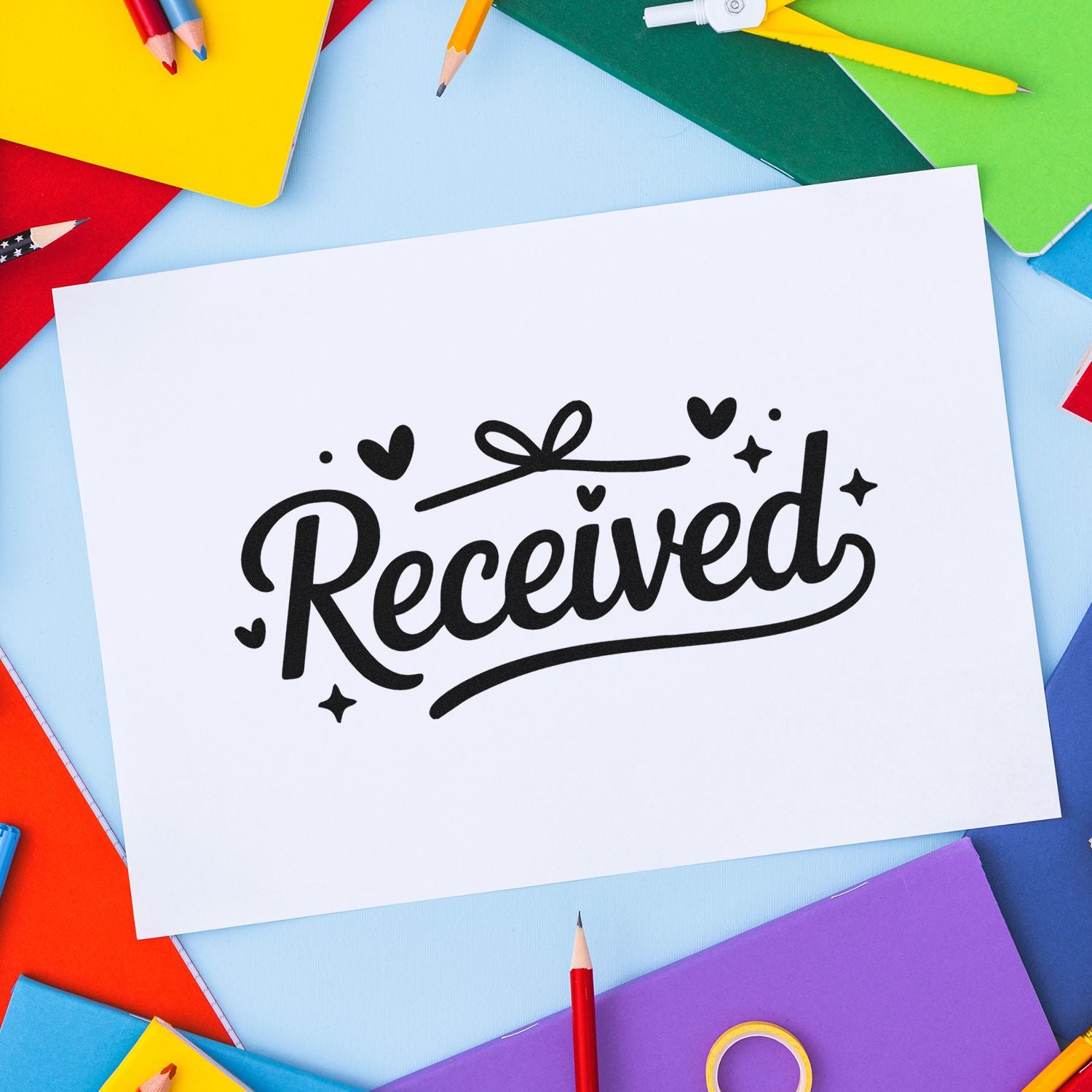 Received rubber stamp design on white paper, surrounded by colorful stationery and pencils.