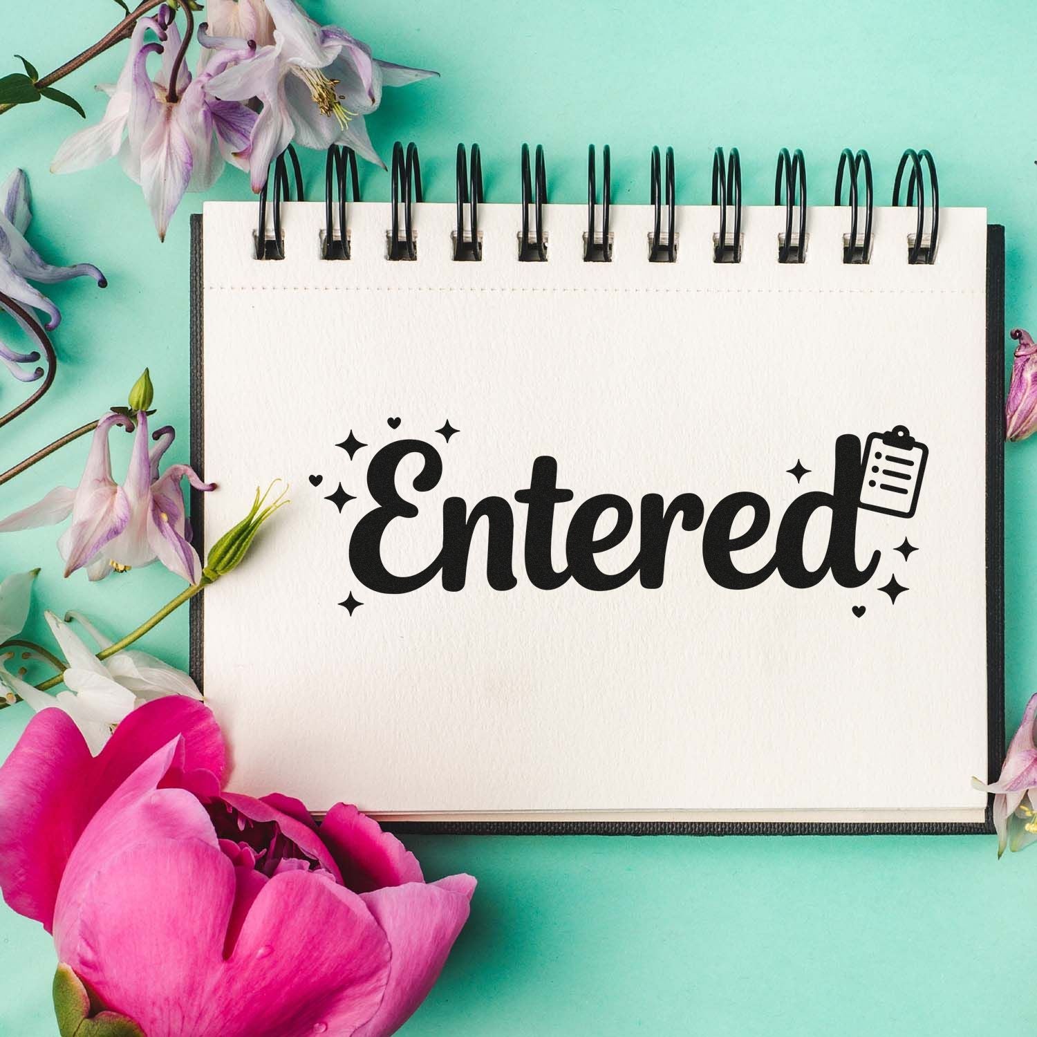 Entered rubber stamp on spiral notebook, surrounded by flowers, for office records, planners, or bookkeeping.