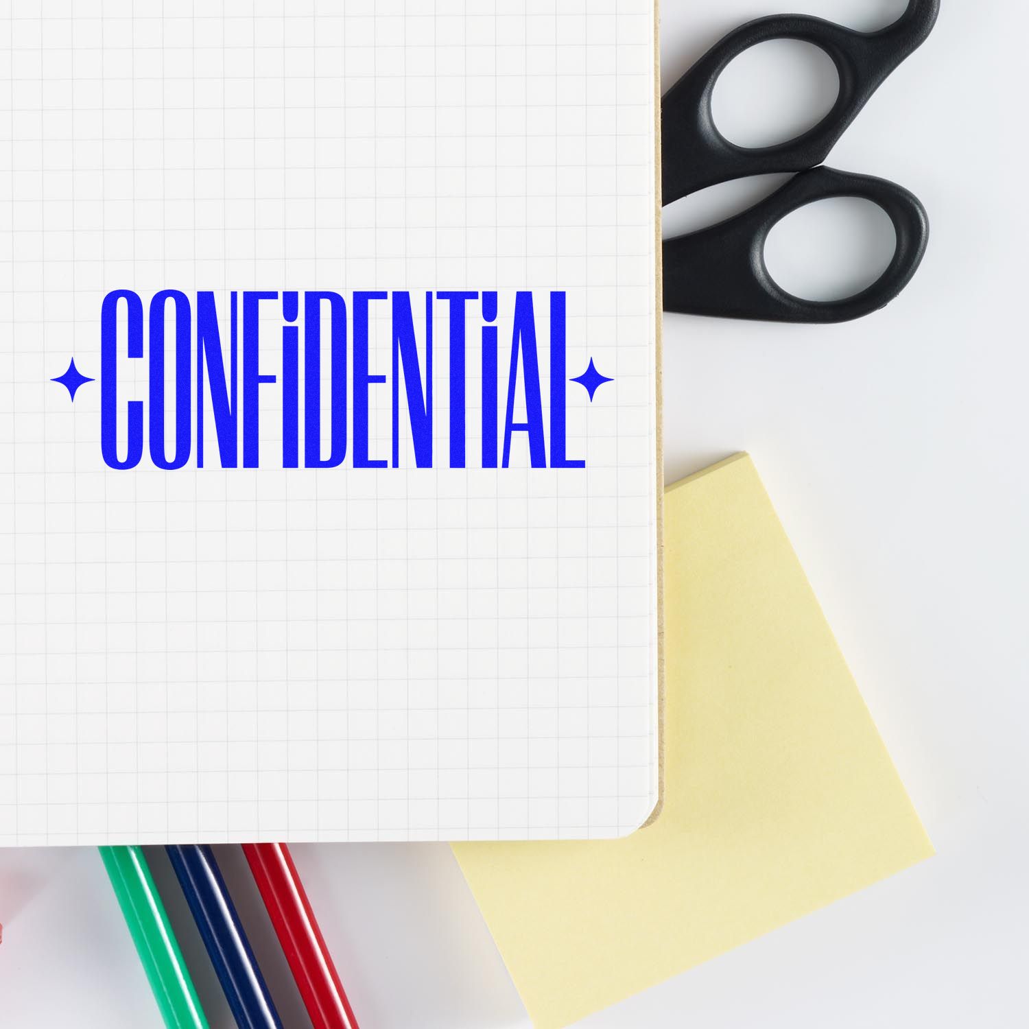 Confidential rubber stamp text on notebook with office supplies, showing a privacy marking for documents.