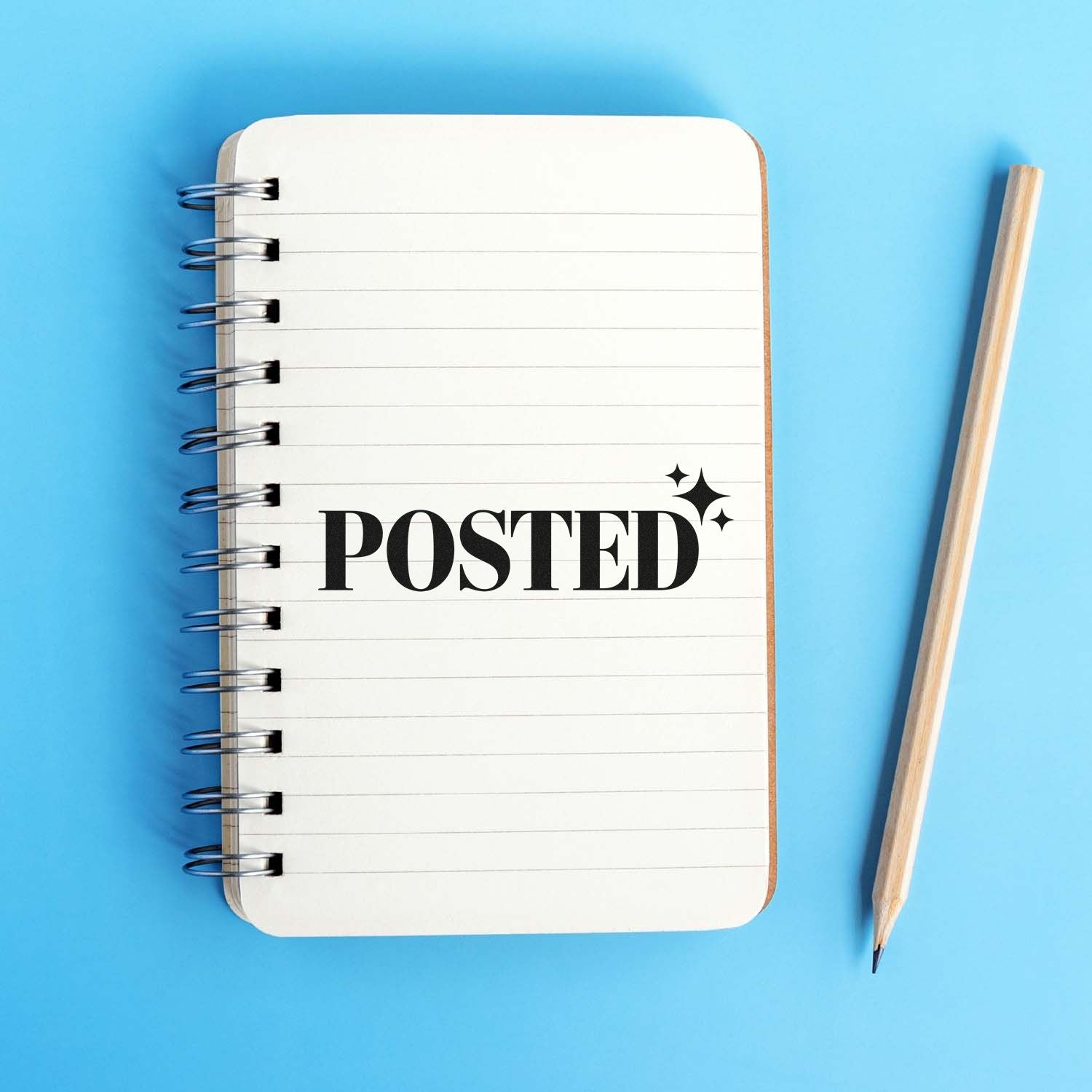Custom rubber stamp with POSTED text on a spiral notebook beside a pencil on a blue background.