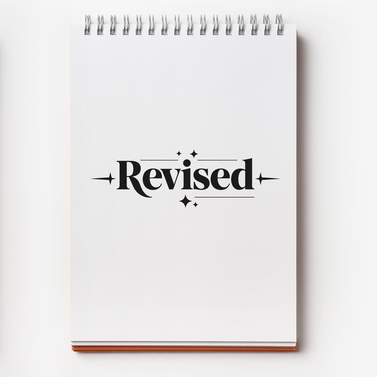 Revised rubber stamp on spiral notebook for proofreading, editing, and document approval.