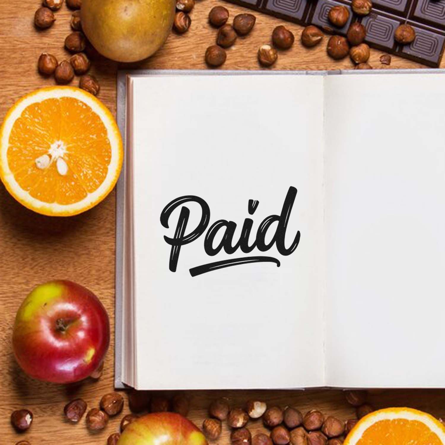 Paid rubber stamp on open notebook for invoice approval, bookkeeping, and office accounting.