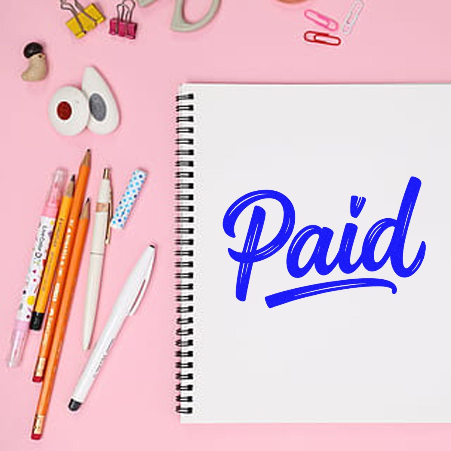 Blue Paid rubber stamp on notebook with stationery, ideal for invoice processing and office organization.