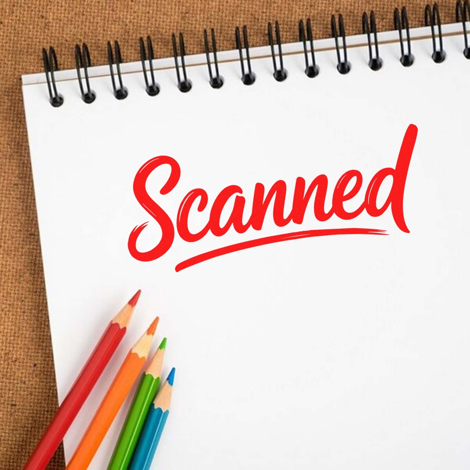 Red Scanned rubber stamp on notebook page with colored pencils, ideal for document processing.