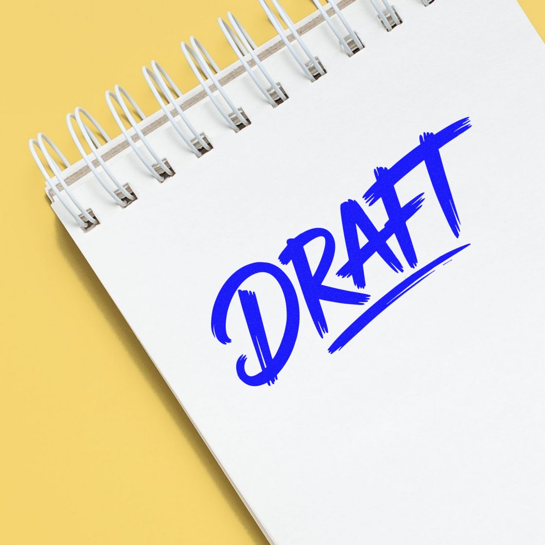 Blue draft rubber stamp on notebook page, marking a document as a draft for review and approval.
