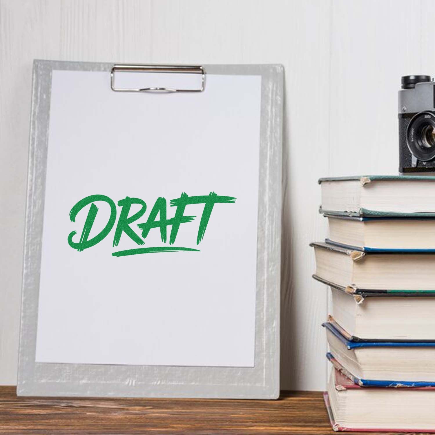 Green DRAFT rubber stamp on clipboard, marking a document as draft for office or editing use.
